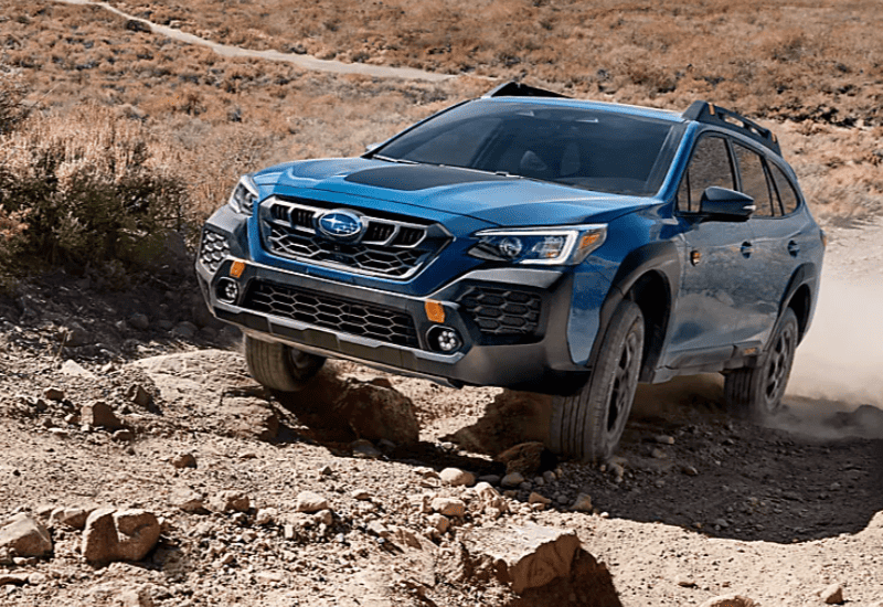 Blue Subaru Outback Driving Off-road in a Rugged Desert Landscape