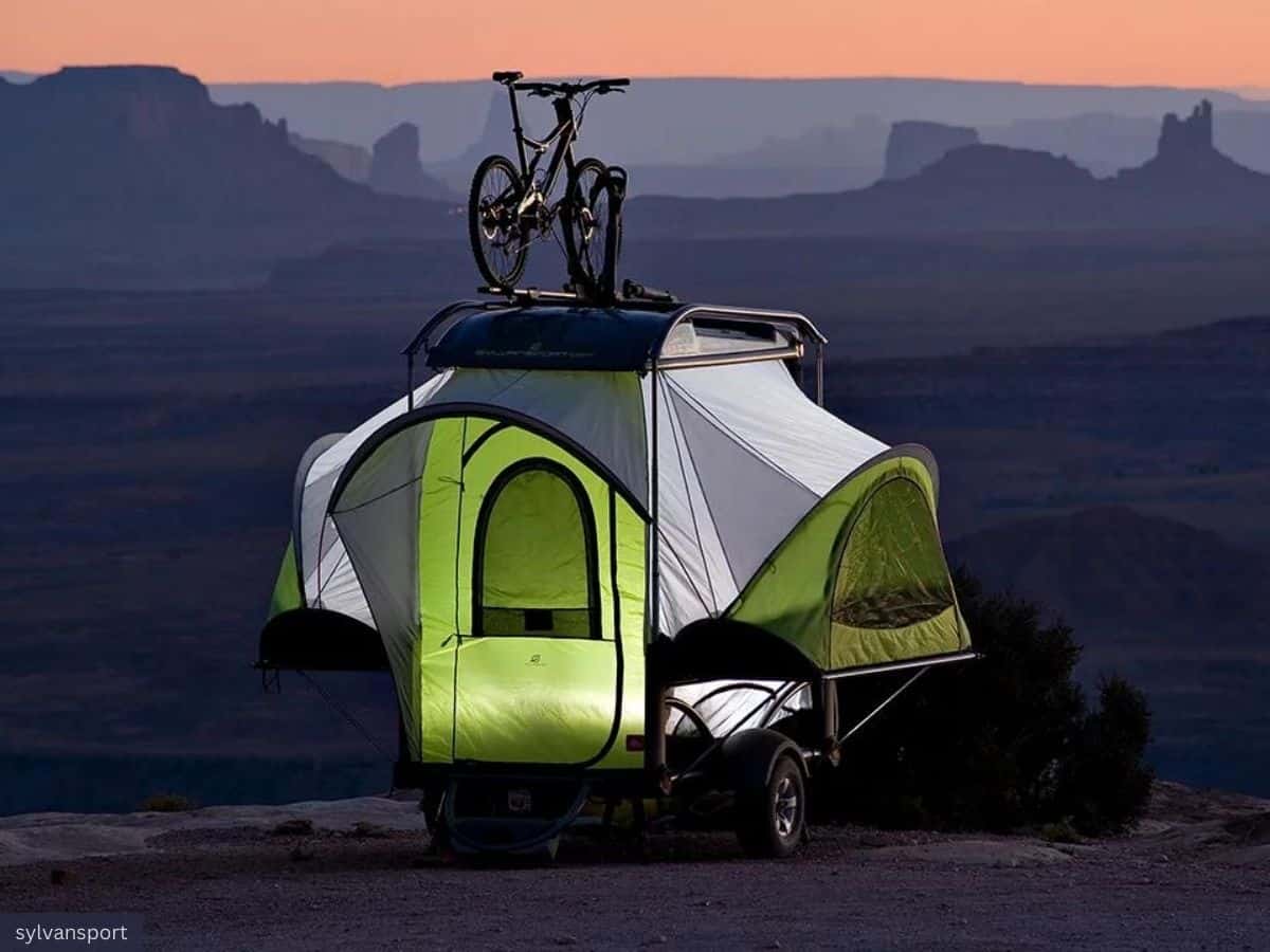 SylvanSport GO Camper Set Up During Twilight with a Stunning Backdrop of Distant Silhouetted Mountains Under a Gradient Evening Sky, Transitioning from Soft Orange Hues Near the Horizon to Deepening Blues