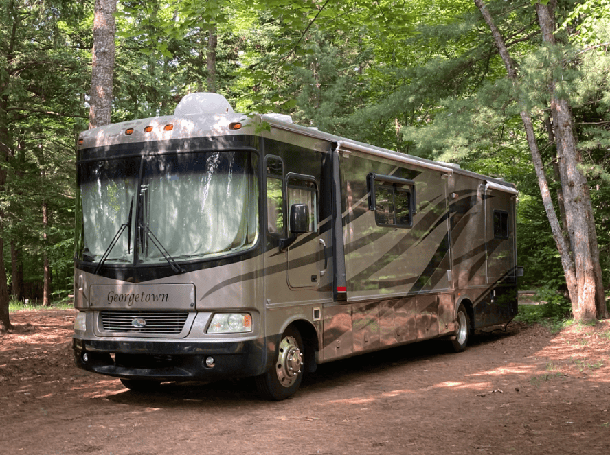 Large Class A Motorhome, Branded "Georgetown," Parked in a Serene Forest Setting.