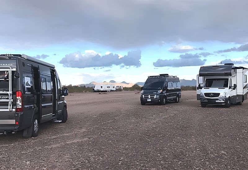 Various RVs Parked on a Vast, Open Gravel Lot Under a Cloudy Sky