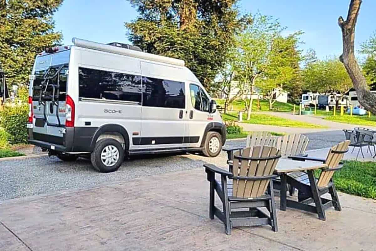 Silver Class B RV Parked at a Campsite with Surrounding Trees