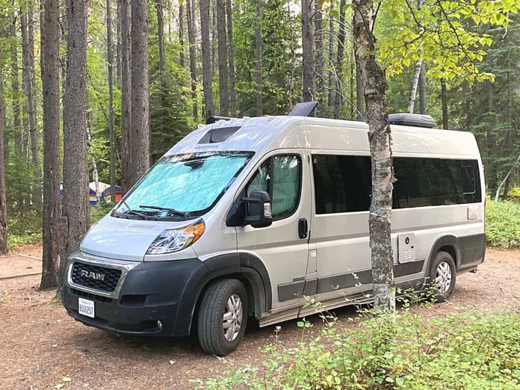 RAM ProMaster Camper Van in a Wooded Campground Parked Close to Several Trees