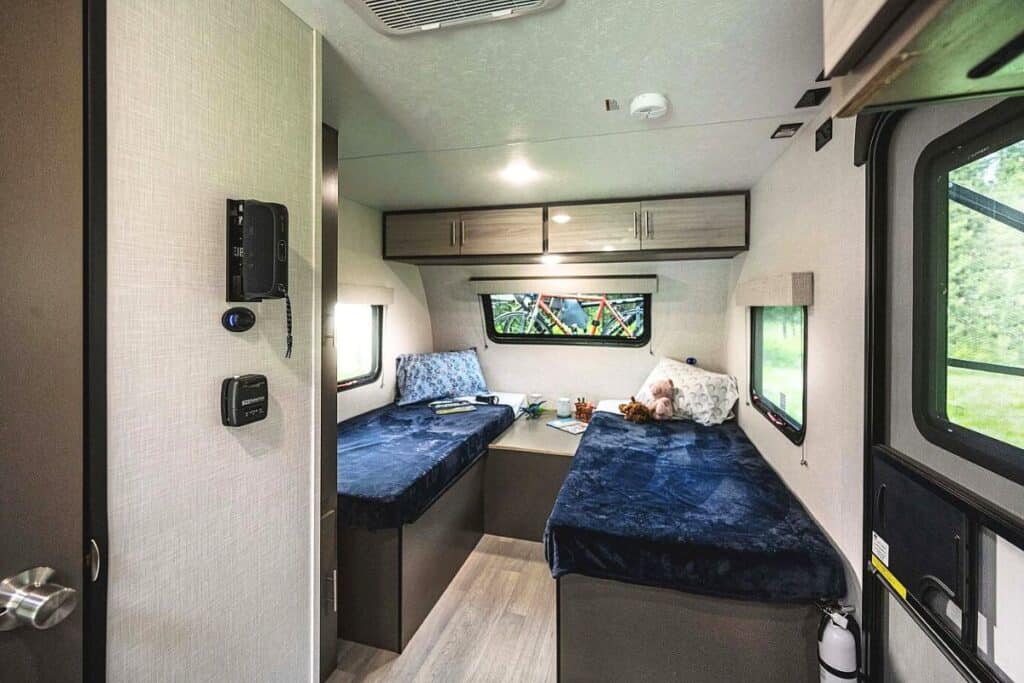 The interior of the KZ RV Escape E20 HATCH showcasing its twin beds with blue bedding on either side of a central walkway.